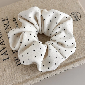 Detail of soft fabric polka dot scrunchie placed on an aesthetic vintage book page