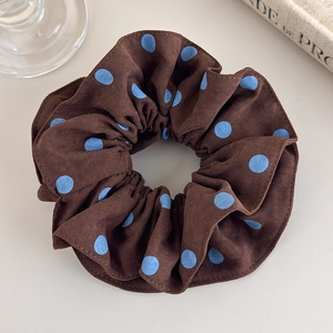 Detail view of vintage brown and blue polka dot fabric scrunchie on a cozy background