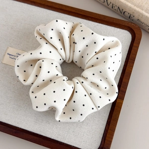 Detail of French polka dot scrunchie with soft fabric texture in linen tray
