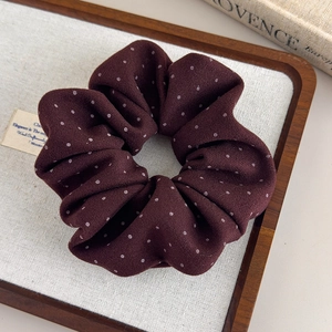 Close-up of burgundy polka dot fabric scrunchie on a vintage wooden tray display