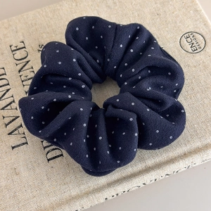 Detail of navy blue polka dot scrunchie with soft fabric texture and elastic structure