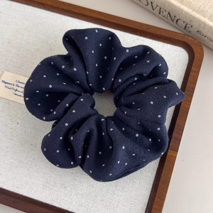 Detail of black polka dot fabric scrunchie on a linen tray with Provence book