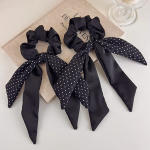 Close-up of elegant black satin and white polka dot bow scrunchies on a vintage book