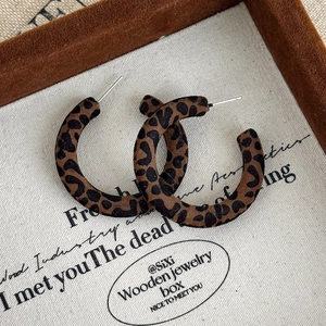 Dettaglio degli orecchini vintage a forma di C con texture leopardata e finitura floccata