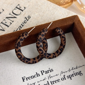 Dettaglio di orecchini a cerchio C leopardati vintage con texture floccata e perni argento