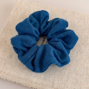 Détail d'un chouchou en maille bleu marine avec texture douce posé sur un livre décor