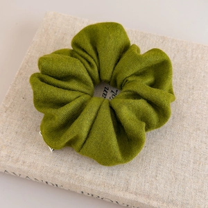 Texture détaillée du chouchou en maille vert olive avec une petite étiquette blanche tissée