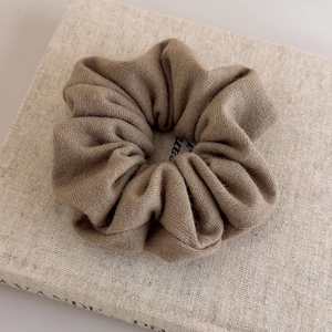 Détail d'un chouchou en tricot marron café montrant la texture douce du tissu sur un livre