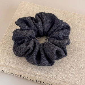 Détail d'un chouchou en maille gris foncé sur un livre montrant la texture en laine