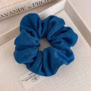 Gros plan d'un chouchou en maille bleu marine doux sur un plateau beige texturé
