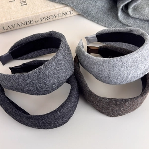 Close-up of thick knitted winter headbands in dark grey, coffee, and light grey shades