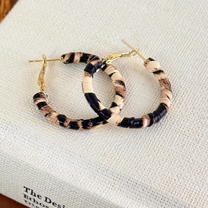Dettaglio di orecchini a cerchio in tessuto leopardato con chiusura a cerniera in oro 18K