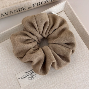 Gros plan sur un grand chouchou en tricot doux marron rétro sur lin naturel