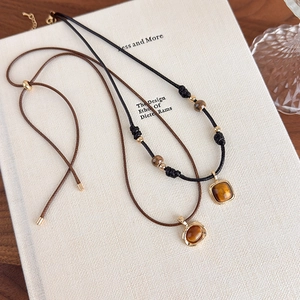 Detail of vintage tiger eye stone pendants on leather cords with polished gold-tone hardware