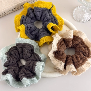 Detail of color-blocked knitted scrunchies with subtle sequins on a decorative tray