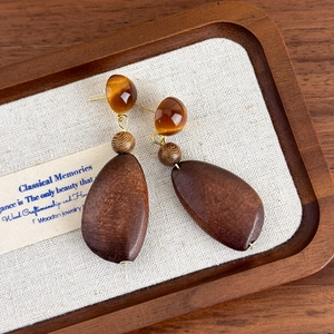 Detail of vintage geometric wooden earrings with dark brown drop pendants and resin studs