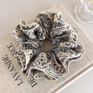 Detail of vintage black and white paisley pattern fabric on a textured cotton scrunchie