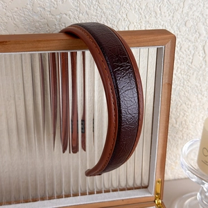 Gros plan du serre-tête en cuir PU marron avec texture crocodile sur support bois