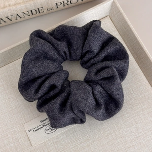Gros plan sur le chouchou en tricot gris foncé montrant les détails de la laine douce