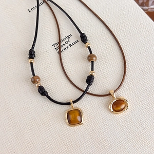 Macro view of tiger eye stone pendants with woven cords on minimalist background