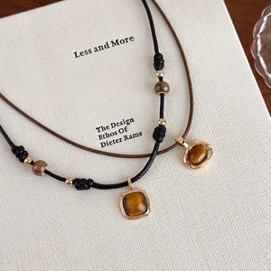 Detail of vintage tiger eye pendants with gold alloy accents on black and brown cords