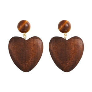 Macro shot of geometric wooden heart earrings with brown cat-eye beads and gold details