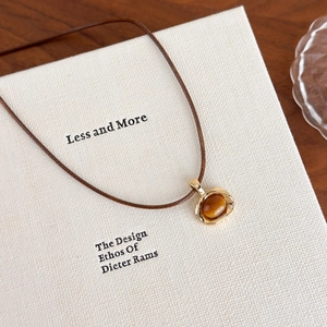 Macro shot of tiger eye stone pendant in gold setting with brown leather cord