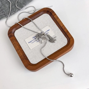 Silver horse necklace with diamonds and metal fringe detail on a soft woven background