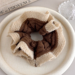 Close-up of contrast knit scrunchie with silver sequins and lace edge on textured tray