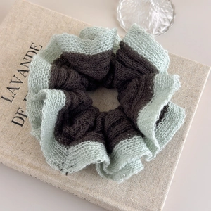 Detail of mint green and brown knit scrunchie with sequins on textured linen fabric