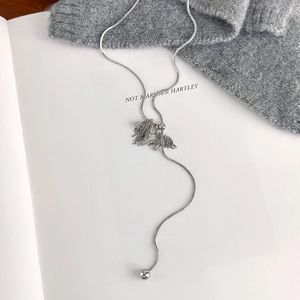 Detail of silver unicorn horse pendant with tassels and snake chain on knitwear
