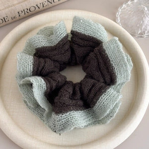 Close-up of mint green and brown knit scrunchie with subtle sequins on a tray