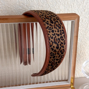 Gros plan du serre-tête en cuir PU marron avec coutures fines et motif léopard