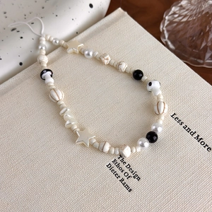 Detail shot of handmade phone strap with black and white beads, stars, and mushrooms