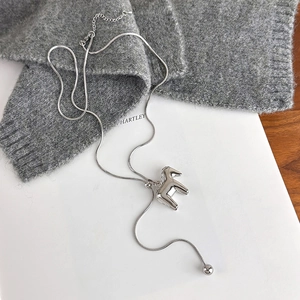 Detailed shot of a silver horse pendant necklace on a soft grey knit sweater
