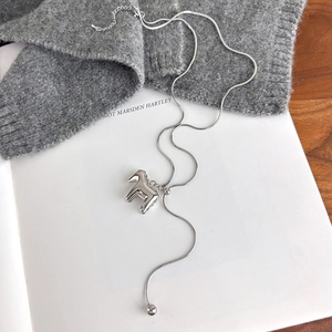 Detail of silver horse pendant with snake chain and tassel ball on an open book