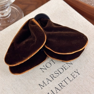 Close-up of deep brown velvet butterfly hair claw clip on a rustic linen book cover