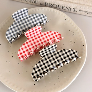 Three-piece checkered acetate claw clip set in blue, red, and black on ceramic tray