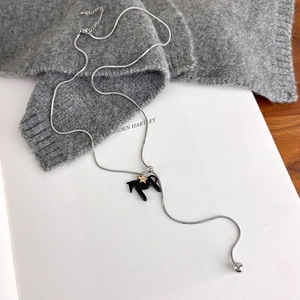 Detail of silver snake chain necklace with black pony pendant and gold star accent