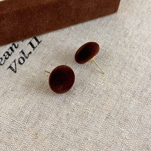 Dettaglio ravvicinato di orecchini a sfera floccati marroni con texture vellutata