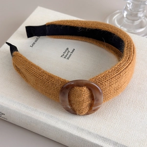 Détail d'un bandeau en tricot jaune avec boucle en résine ambre texturée