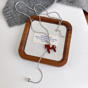 Macro shot of silver snake chain with red pony pendant and gold star on a tray