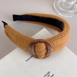 Détail d'un bandeau en maille kaki avec boucle en résine ambrée et texture laine douce