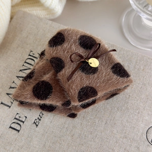 Close-up of brown polka dot plush hair claw with silk bow and handmade metal tag