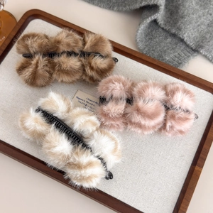 Détail de trois barrettes banane en peluche marron, rose et crème sur un plateau