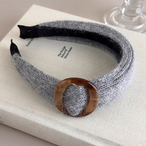 Détail d'un bandeau en maille grise avec anneau en résine brune sur un livre blanc