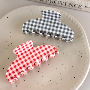 Detailed view of red and grey checkered acetate hair claws on a ceramic dish