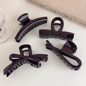 Detail view of four chocolate brown hair claws with bow and geometric shapes in glossy finish