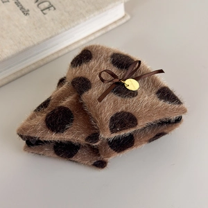 Detailed view of plush triangle hair claw with brown polka dots and a silk bow detail