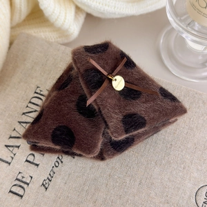 Detail of plush brown polka dot hair claw with a silk bow and golden handmade charm